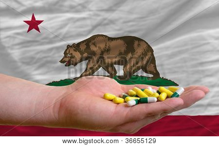 Bedriften piller i hånden foran Californien os stat Flag