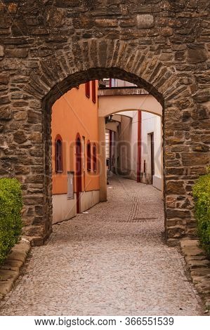Beautiful Stone Gate Near The Medieval Town With A Winding Alley And Colorful Houses