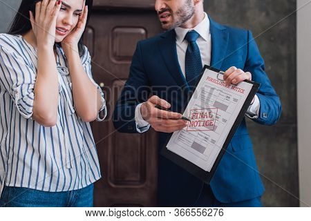 Collector Pointing At Documents With Foreclosure Lettering Near Stressed Woman In Room