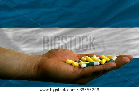 Tenendo In mano pillole davanti alla bandiera nazionale di El Salvador
