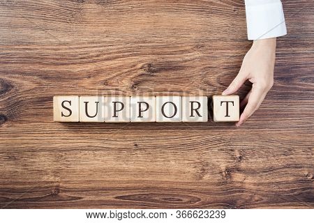 Support Text On Building Blocks On Rustic Wooden Background. Female Hand Holds The Last Block. Medic