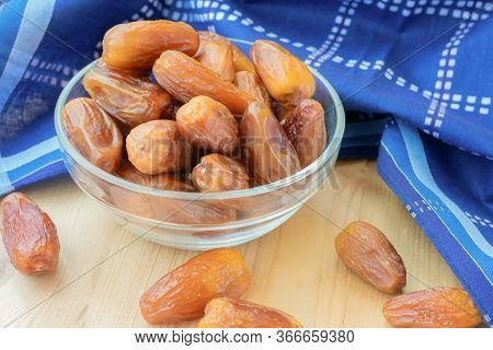 Close Up View Of Dried Sweet Deglet Nour Date Fruites In Translucent Bowl And Dark Blue Napkin.organ