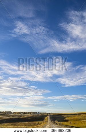 A Gravel Township Road On The Prairies In The Early Morning With A Clear Cloudy Blue Sky In Farm Cou