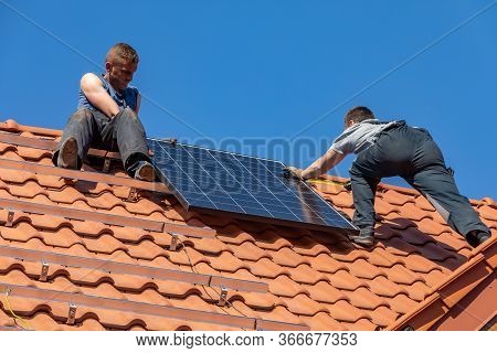 Ochojno, Poland - April 8, 2020: Workers Installing Solar Electric Panels On A House Roof In  Ochojn