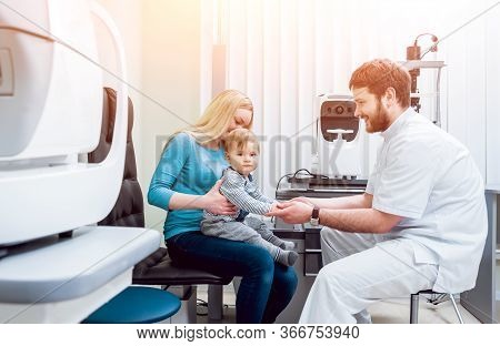 Basic Eye Examination. Mother Holds Child During Eye Exam.