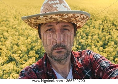 Rapeseed Farmer Making Selfie Portrait In Cultivated Field, Close Up Headshot With Selective Focus