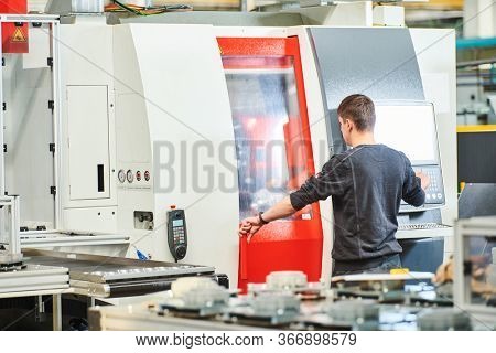 Industrial worker operating cnc machine at metal machining industry