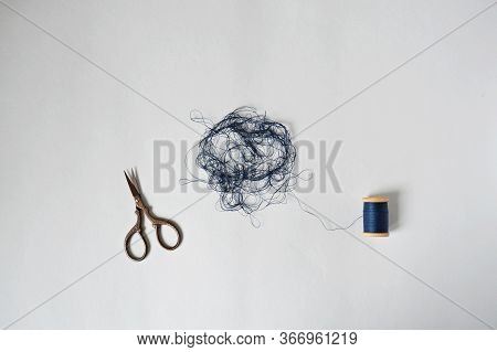 Blue Tangle Thread Spool And Scissors Over White