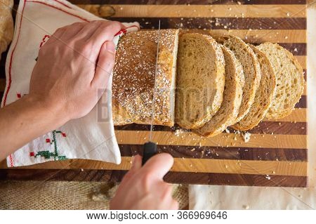 Baker Cutting Crusty French Loaf On Chopping Board. Closeup Shot, Top View. Traditional Food Or Baki