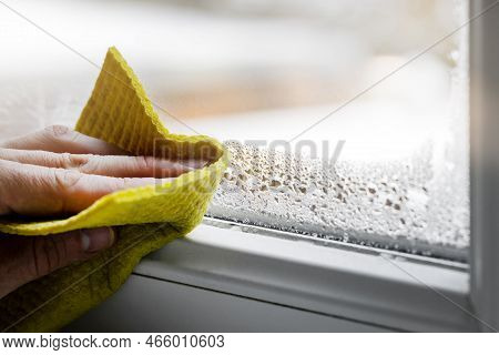 High Humidity In The House. Hand Wipes Off Water Condensation From Plastic Window Glass In The Room.