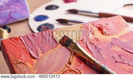 Artist's Canvas With Mixed Paints And Brush On Wooden Table, Closeup