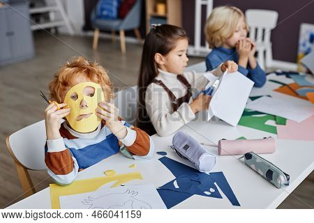 Cute Gingerhaired Little Boy With Yellow Handmade Paper Mask On His Face Looking At Camera Through H