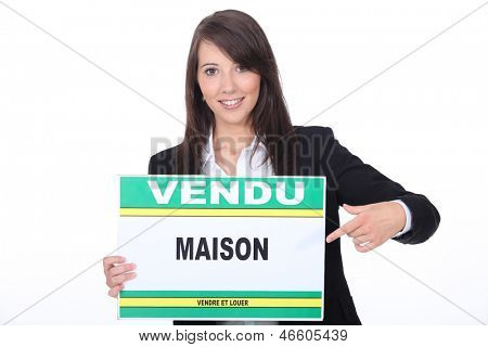 Agente immobiliare francese con un segno 'Vendu'