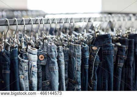 Close Up Of Blue Denim Jeans In Row On Clothing Rack At Thrift Shop, Copy Space