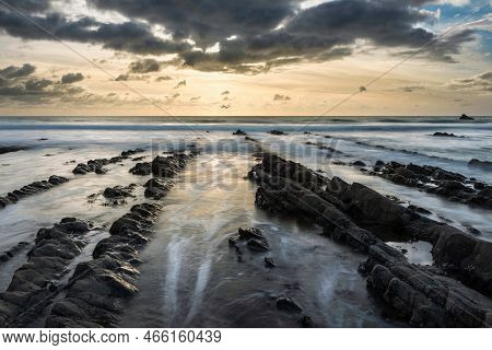 Stunning Sunset Landscape Image Of Welcome Mouth Beach In Devon England With Beautiful Rock Formatio