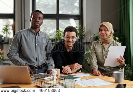Group Of Three Happy Young Intercultural Employees Looking At Camera