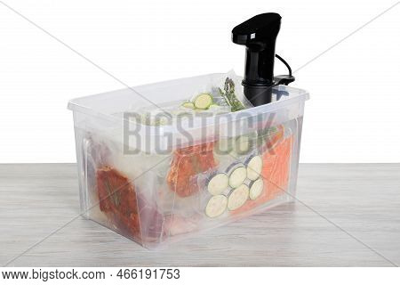 Sous Vide Cooker And Vacuum Packed Food Products In Box On Wooden Table Against White Background. Th