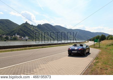 Bad Salzig, Germany - June 26, 2021: Blue Roadster Porsche Boxster 986 With River Rhine Gorge And Ca