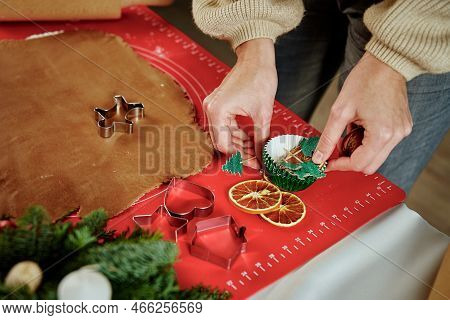 Woman Preparing Gingerbread Cookies At Kitchen With Christmas Decorations. Female Hands Cutting Ging