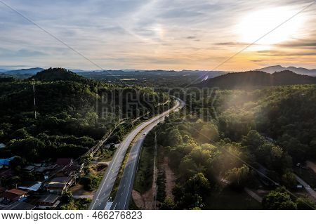Aerial Landscape Of 4 Lane Road With Residential Area, Forest, Mountain,  Blue Sky And Sunlight With