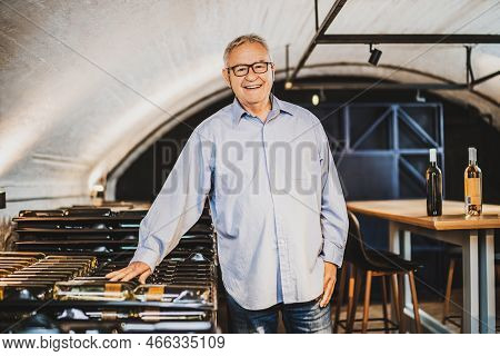 Portrait Of Senior Man Who Owns Winery. He Is Examining Quality In His Wine Cellar. Industry Wine Ma