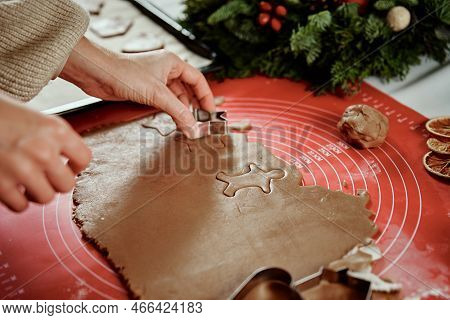 Woman Preparing Gingerbread Cookies At Kitchen With Christmas Decorations. Female Hands Cutting Ging