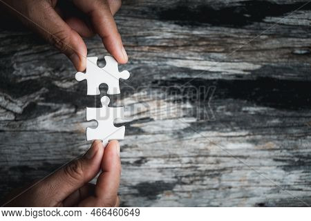 Pieces Of Jigsaw Puzzle In Woman's Hands. White Details Of Jigsaw Puzzle Piece On Wooden Background.