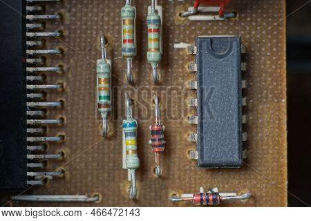 Part Of An Old Brown Chip With A Black Transistor And Colored Diodes