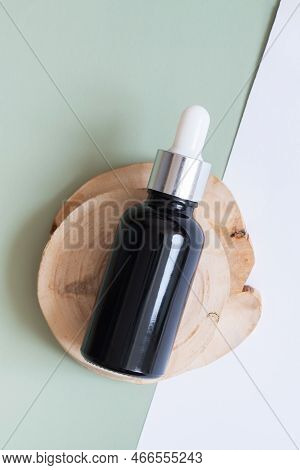 Cosmetic Bottle With Pipette On Wooden Slice Top View, Flat Lay On Colored Background. Natural Cosme
