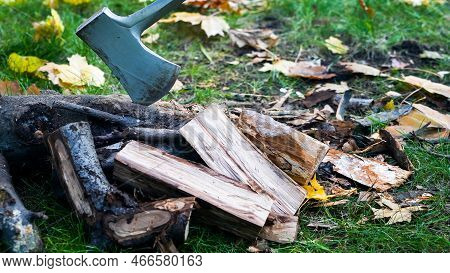 Close Up From Axe  With Wood Outside In Autumn With Leaves Around