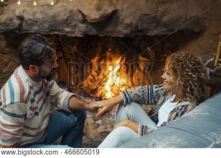 Happy Young Couple In Romantic Leisure Activity At Home Enjoying Fireplace To Heating Home. Romance 