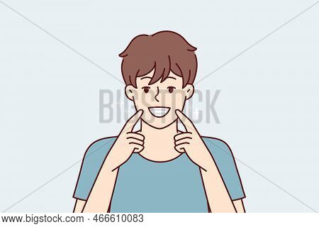 Man Smiles Broadly And Shows Off Snow-white Healthy Teeth After Going To Dentist. Happy Guy Pointing