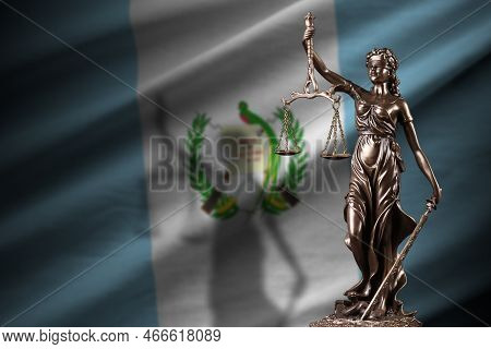 Guatemala Flag With Statue Of Lady Justice And Judicial Scales In Dark Room. Concept Of Judgement An