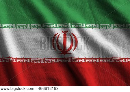 Iran Flag With Big Folds Waving Close Up Under The Studio Light Indoors. The Official Symbols And Co