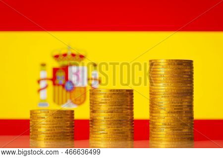 Upgoing Graph Made Of Coins Stacked In Front Of Spain Flag. Concept Of Financial Development Of Spai