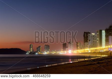 A Mazatlan Sinaloa Beach At Night With Luminous City In The Background