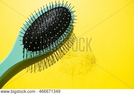 Green Comb And Fallen Hair On The Yellow Background. Baldness And Hair Loss Problem