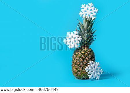 A Whole Pineapple On A Bright Blue Background With Hanging Snowflakes, Copy Space. Pineapple Like A 