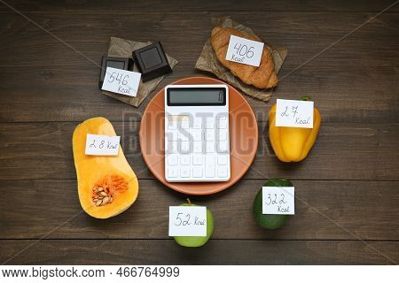 Calculator And Food Products With Calorific Value Tags On Wooden Table, Flat Lay. Weight Loss Concep