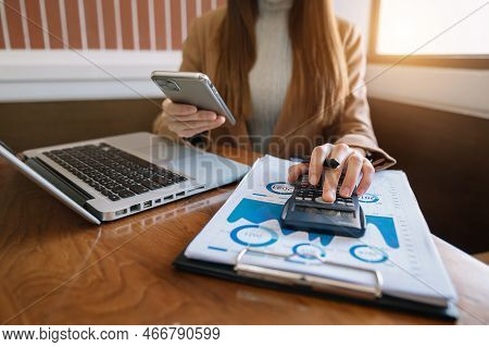 Close Up Of Businesswoman Or Accountant Hand Holding Pen Working  To Calculate On Desk About Cost At