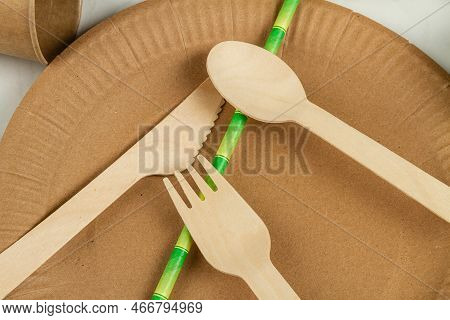 Top View Close Up Wooden Utensils And Green Straw. Plate With Flork And Spoon.