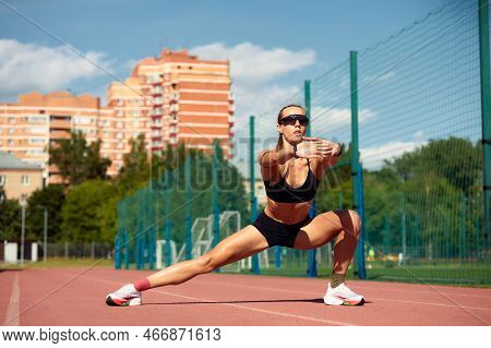 Young Woman Runner Warming Up At The Racetrack. Fit Runner Workout, Stretch Her Muscle And Warming U