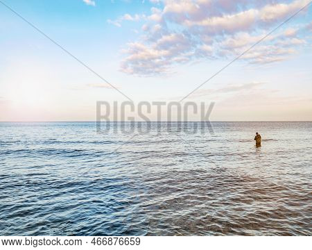 Fisher Man Stay In The Water And Pulling Bait On His Fishing Rod. Baltic Shore, Germany