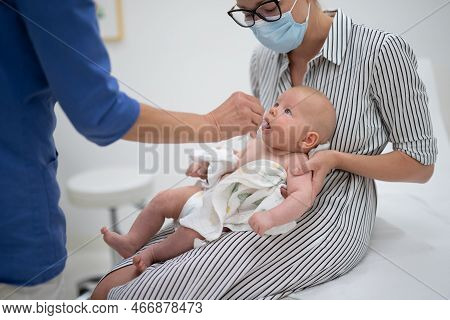 Pediatrician Administring Oral Vaccination Against Rotavirus Infection To Little Baby In Presence Of