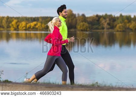 Jogging Concepts. Running Couple While Training Outdoors On Road At River For Durable Marathon Prett