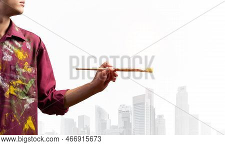 Close Up Artist Hand Holding Paintbrush. Painter In Shirt Standing On Background Modern Skyscrapers.