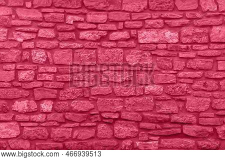 Trendy Color Viva Magenta 2023. A Solid Red Stone Wall Made Of Various Sizes Of Stone