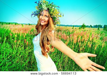 Portræt af en romantisk smilende ung kvinde i en tudorroser af blomster udendørs.