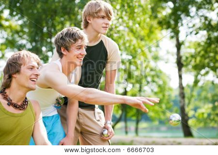 Gruppo di giovani uomini giocando boule in un lago