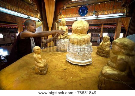 Buddhish Monk is gilding gold leaf at famous five small Buddhas